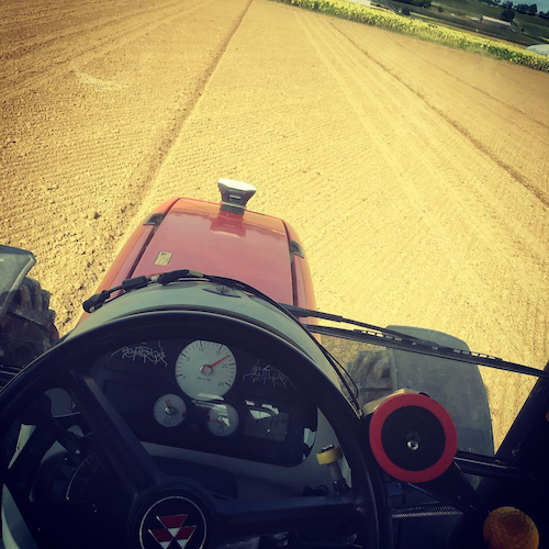 precision agriculture technology: a tractor with Reach GNSS receiver driving through a field. 
