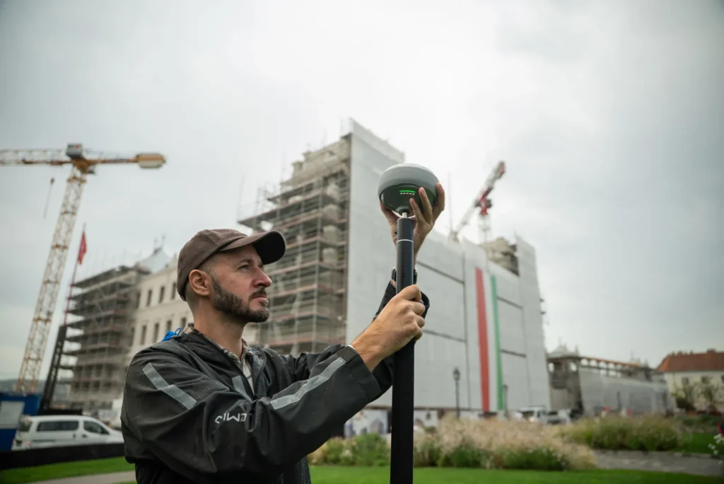 GNSS field verification on a construction site as a surveyor checks positioning accuracy before work continues.